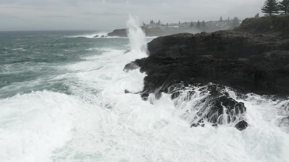 Fly around shot of angry ocean exploding onto the rocky shore line ...