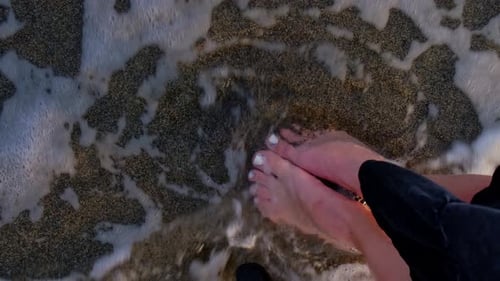 Female Legs and Feet Walking Along Sea Water Waves on Sandy Beach