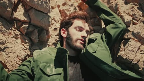 Lifeless body of man with arms spread wide on jagged rocky terrain in desert