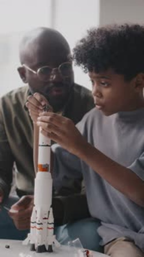 African American Boy Constructing Rocket Model with Father