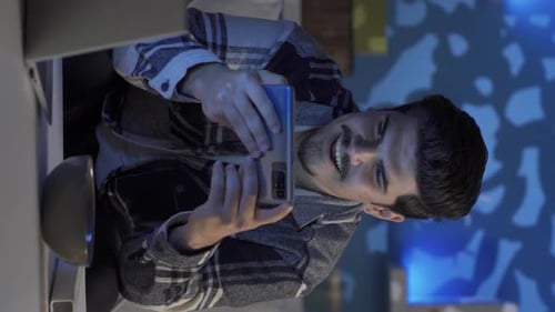 Vertikales Video eines jungen Mannes, der sich erstaunt ein Video am Telefon ansieht und Alkohol trinkt.