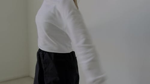 Female Dancer Stretching Shoulders and Wrists beside Wall in Studio