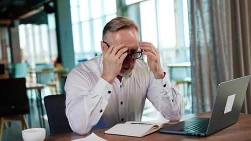 Stressed Man Working at Desk in Bright Office
