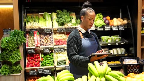 Grocery Store Worker Using Tablet by Produce Display