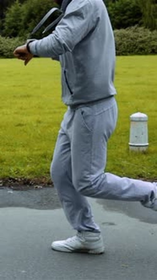 Vertical of Man Running in Green Parkwoods Training and Look at Arm Clock