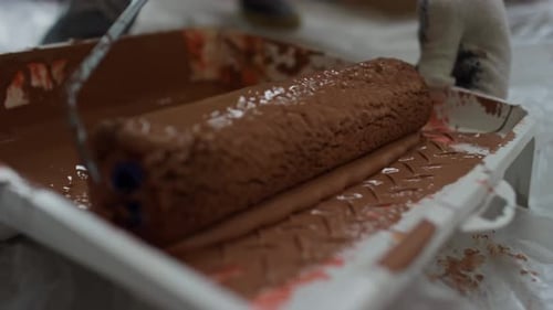 Taking Brown Paint with Paint Roller During House Renovation