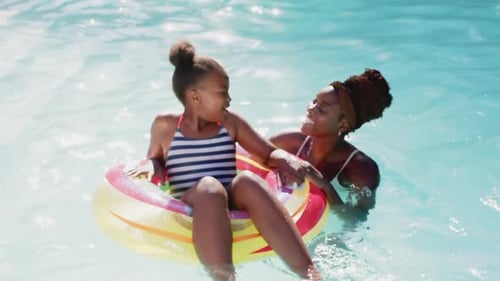 Mutter und Tochter spielen im Pool und genießen den Sommertag mit einem aufblasbaren Ring