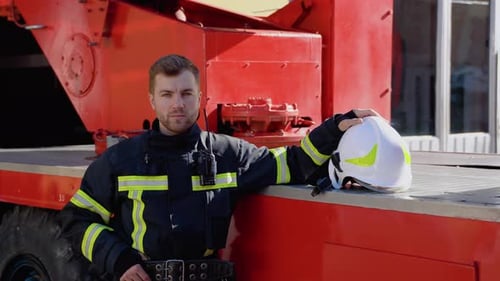 Firefighter in Uniform Leans Against Firetruck