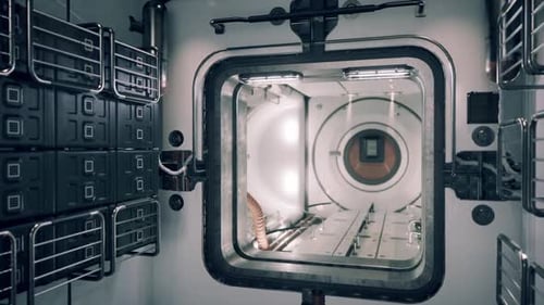 Vue intérieure d'un module de station spatiale montrant un espace de rangement et une trappe d'entrée