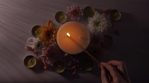 Hand lighting round candle with flowers decoration, top shot