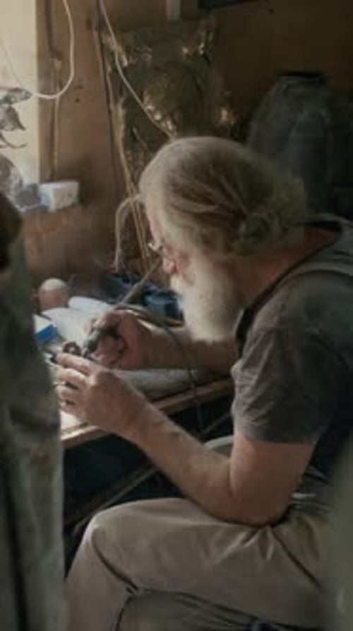 Vertical of Senior Craftsman Soldering in Workshop