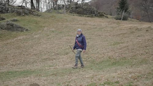 Woman Walking with Dog on Grassy Hillside