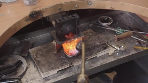 Ein Mann arbeitet an einem Schmuckstück und erhitzt das Metall mit einer Fackel