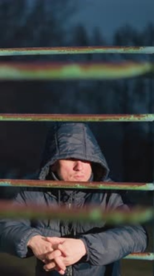 Reflective Moment Two Individuals Resting on Iron Bar with Blurred Urban Background