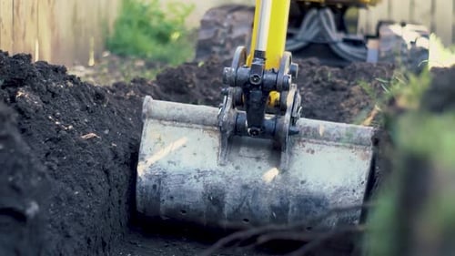 Excavator Digging Trench in Rural Outdoor Setting