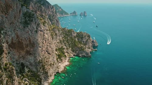 Breathtaking aerial view of Capri coastline with rugged cliffs. The ocean's hues of blue are sprinkl