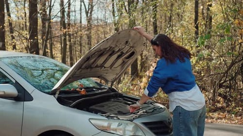 A Breakdown on the Road a Woman Opens the Hood and Looks for a Problem