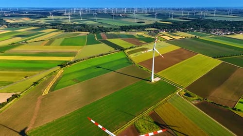 Picturesque agricultural fields with wind farms. Producing green energy from wind power. Aerial view