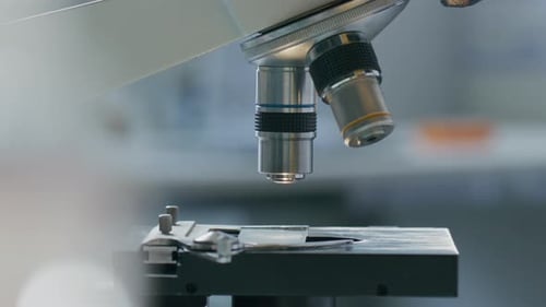 Close-Up of Microscope Objective Lens Being Lowered to Specimen Slide