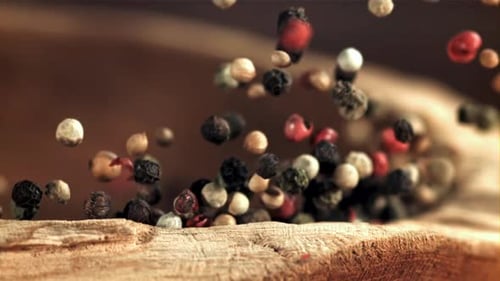 Falling Multi Colored Peppercorns on Wood Surface