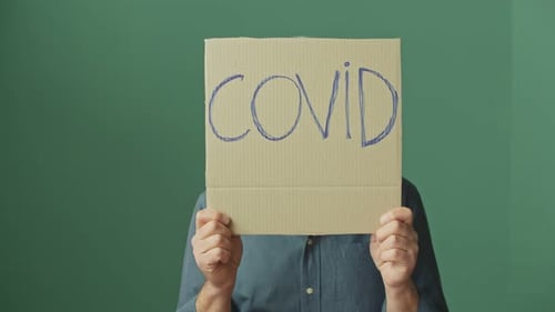 Man Behind a COVID Sign Wearing a Respirator