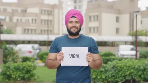 Smiling Man Holds Viral Sign Outdoors