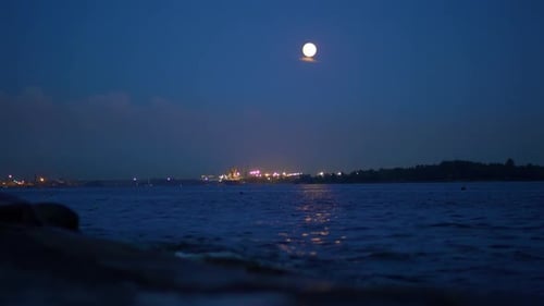 Full Moon Rising Over Water at Night Creating a Mesmerizing Atmosphere