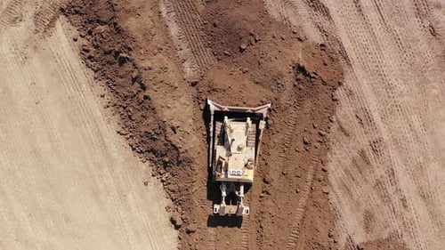 Bulldozer pushing large amount of fresh soil, Aerial follow footage.