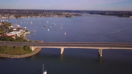 Von oben nach unten atemberaubende Luftaufnahme einer langen Brücke über die Bucht und den Kai mit Blick auf Boote