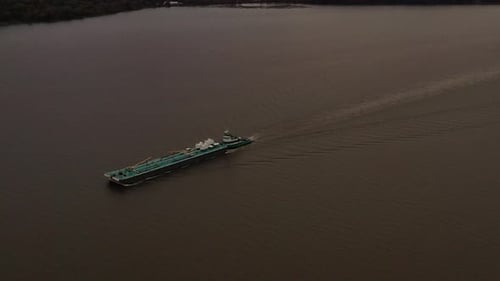aerial shot over a turqiuse colored barge & tugboat on the Hudson River on a cloudy evening in Beaco