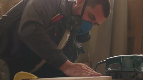 Man Sands a Piece of Wood Indoors