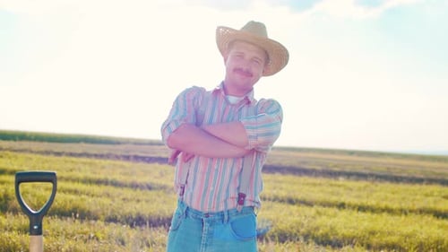 Portrait Shot of the Caucasian Man Farmer Standing in the Middle of the Wheat Field in the Sunlight