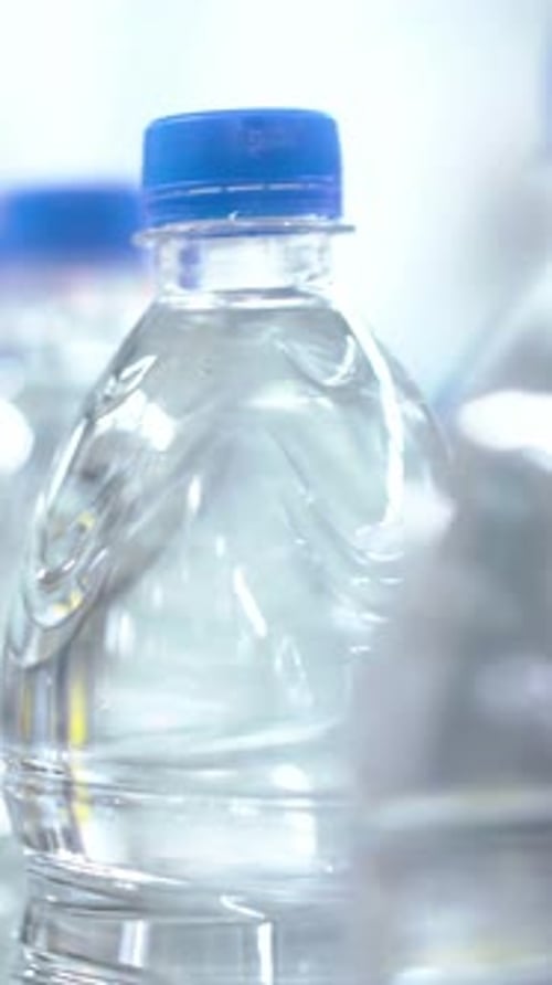 Vue rapprochée de bouteilles d'eau transparentes en pleine lumière sur un marché animé