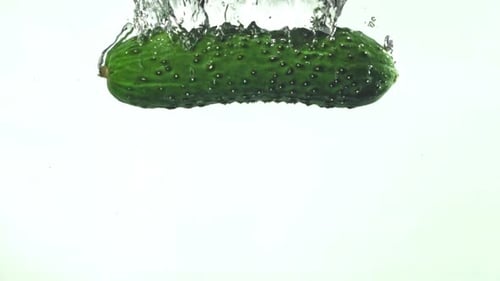 Cucumber splashing into crystal clear water with bubbles