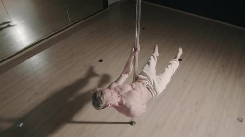 Handsome Man with Bare Torso Pole Dancing in Studio
