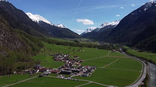 Malerisches Bergdorf im grünen Tal zwischen steilen Alpenbergen, aus der Luft