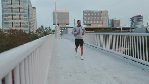 Athletic Man Jogging Across a Bridge in the City