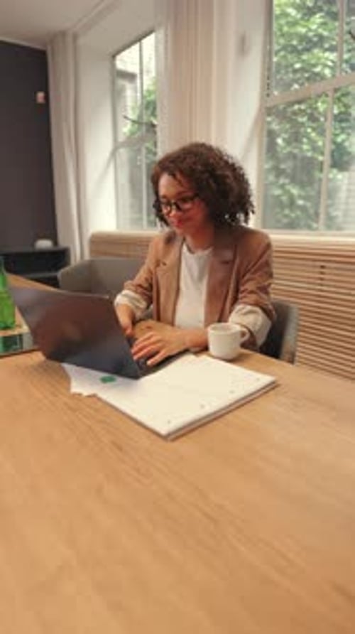 Confident Business Woman Sitting at Desk with Laptop in Bright Modern Office