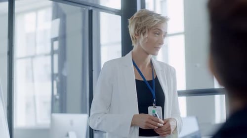 Una mujer con una chaqueta blanca lidera las discusiones que muestran el trabajo en equipo