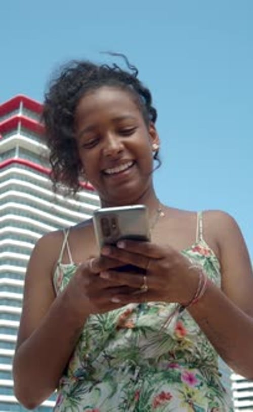 Vertical videoCarefree African American Young Woman Chatting in a City in Summer