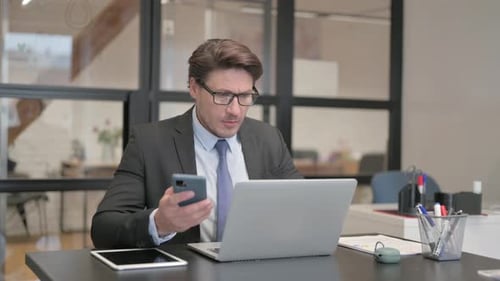 Focused Businessman Using Smartphone at Office Desk