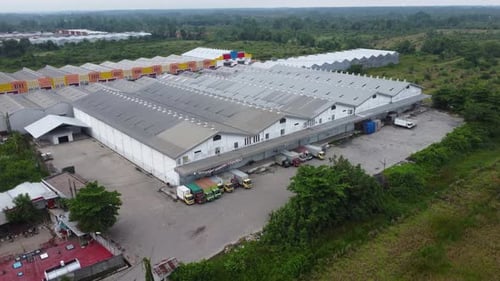 Aerial view of a goods distribution warehouse lined up with goods trucks parked in front of the ware
