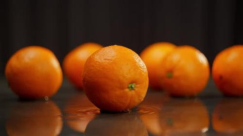 Oranges are Spread Out on the Table and One is Spinning in the Foreground