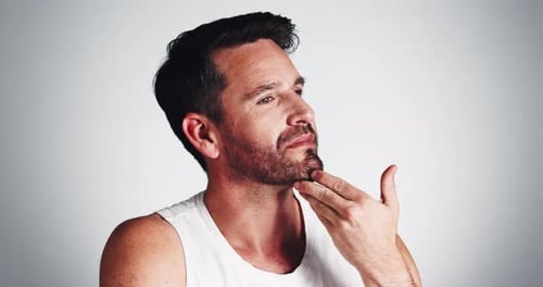 Studio, routine and man with beard, touch and smile for fresh shave, grooming and facial treatment