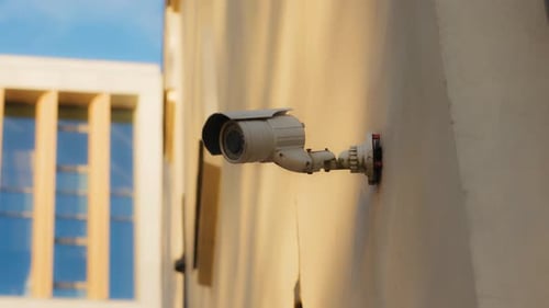 A CCTV Camera Mounted on a Wall of a Corporate Building in the Evening