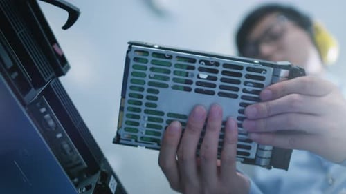 Im Rechenzentrum: IT-Ingenieur installiert neue HDD-Festplatte und andere Hardware im Server-Rack Equ