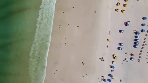 beach with a green sea up to down view with people having fun in a summer holiday day and umbrellas