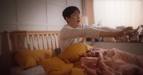 Young Man Waking Up and Stretching in Bed