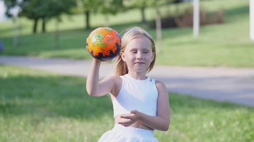 Niña alegre jugando con una pelota en el parque