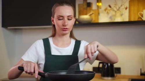 Woman Cooking with Frying Pan in Kitchen